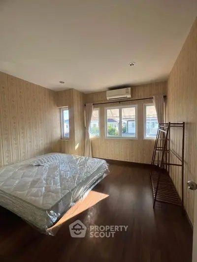 Spacious bedroom with natural light and wooden flooring
