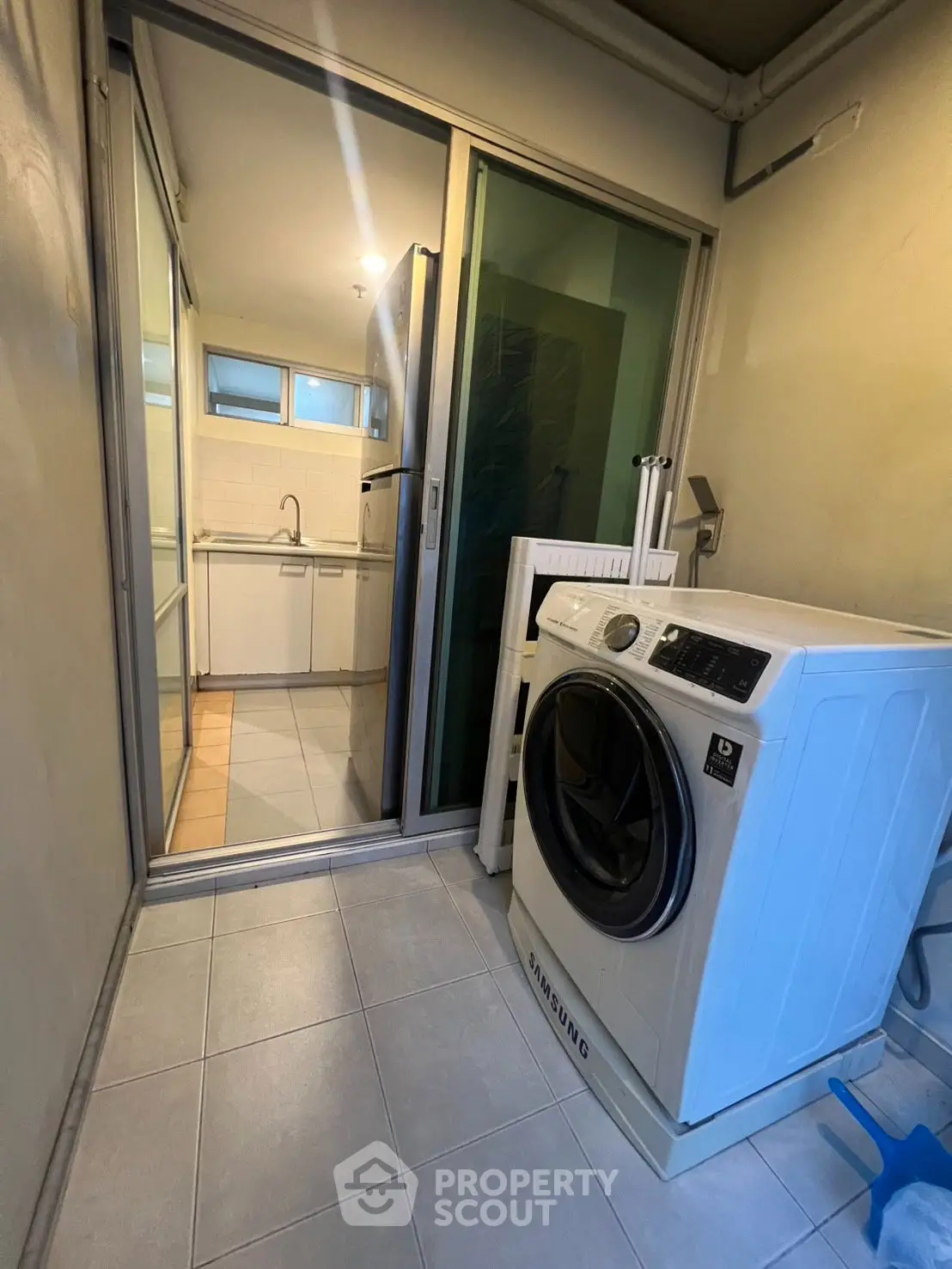 Modern laundry area with washing machine and sliding glass door leading to kitchen.