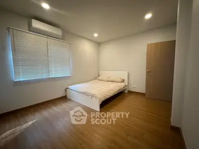 Spacious minimalist bedroom with wooden flooring and natural light