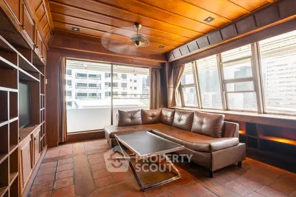 Spacious living room with wooden ceiling and large windows offering city views.