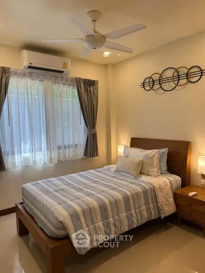 Cozy bedroom with modern decor, featuring a comfortable bed, stylish wall art, and natural light from a large window.