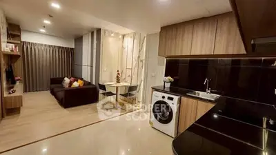 Modern open-plan living room and kitchen with sleek design and cozy seating area.