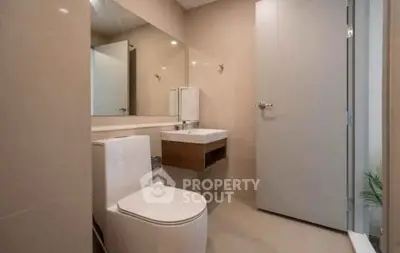 Modern bathroom with sleek fixtures and minimalist design, featuring a wall-mounted sink and large mirror.