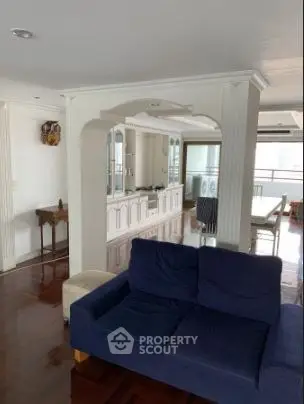 Spacious living room with elegant wooden flooring and stylish blue sofa in a modern apartment.