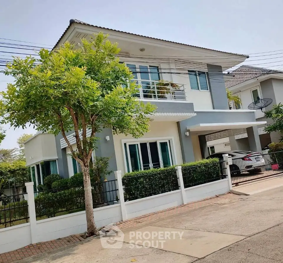 Charming two-story house with modern design, lush greenery, and spacious driveway in a serene neighborhood.
