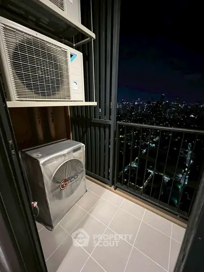 Modern balcony with city skyline view and air conditioning units at night.
