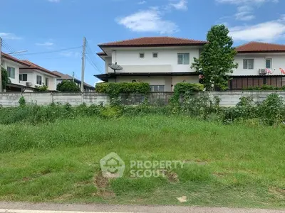 Spacious residential plot with lush greenery and modern houses in a serene neighborhood.