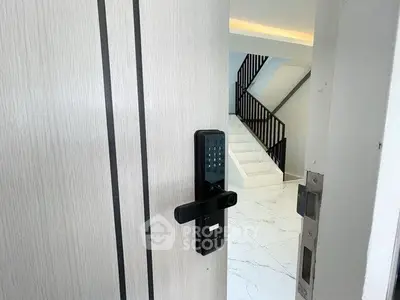 Modern entryway with digital lock and sleek staircase in luxury home