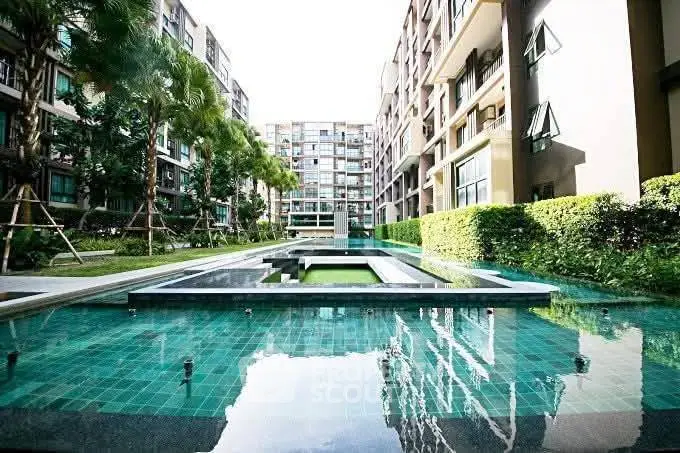 Luxurious apartment complex with modern pool and lush greenery, perfect for urban living.