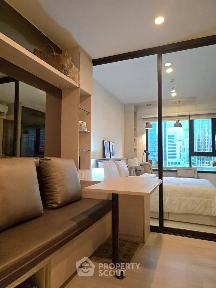 Modern bedroom with city view, featuring sliding glass doors and cozy seating area.