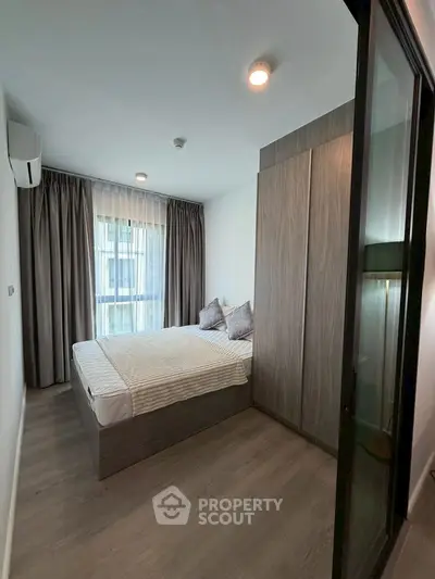 Modern bedroom with large window and stylish decor in a contemporary apartment.