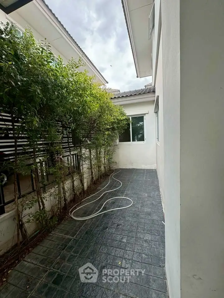 Charming outdoor space with tiled flooring and lush greenery, perfect for relaxation and gardening.
