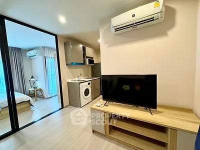 Modern apartment interior with open living room and kitchen, featuring air conditioning and washing machine.