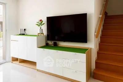 Modern living room with sleek TV setup and stylish storage cabinets near staircase.