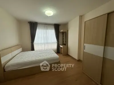 Spacious bedroom with modern furnishings and large window for natural light.