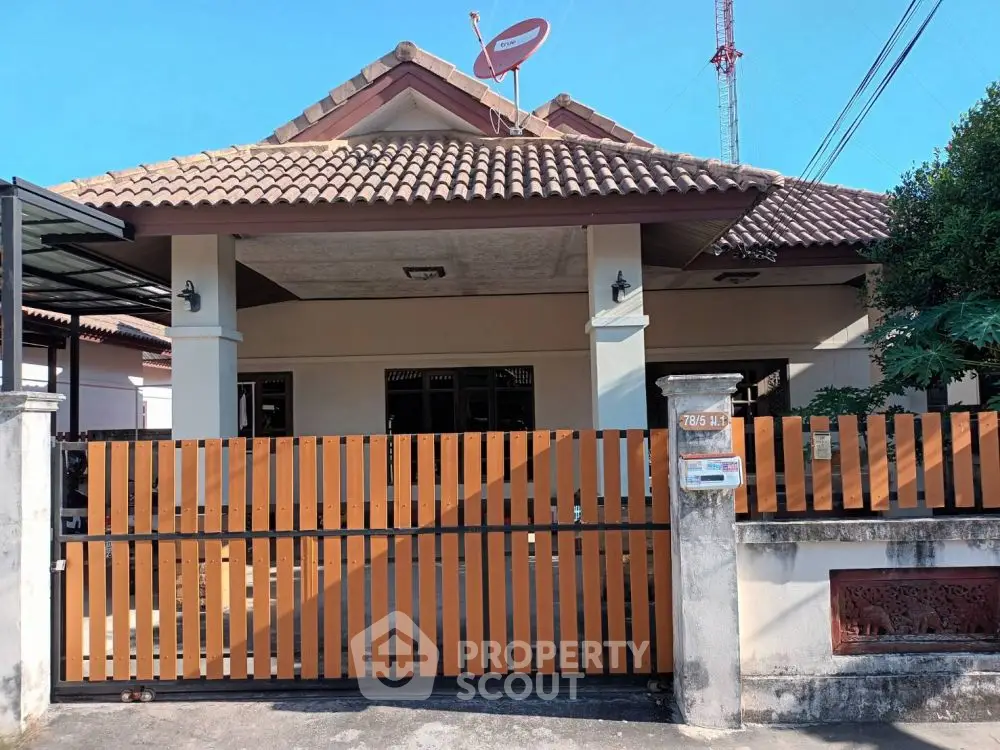 Charming single-story home with tiled roof and gated entrance, perfect for family living.