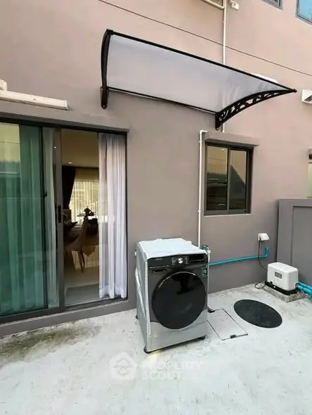 Modern outdoor laundry area with washing machine and sliding glass door access to interior.