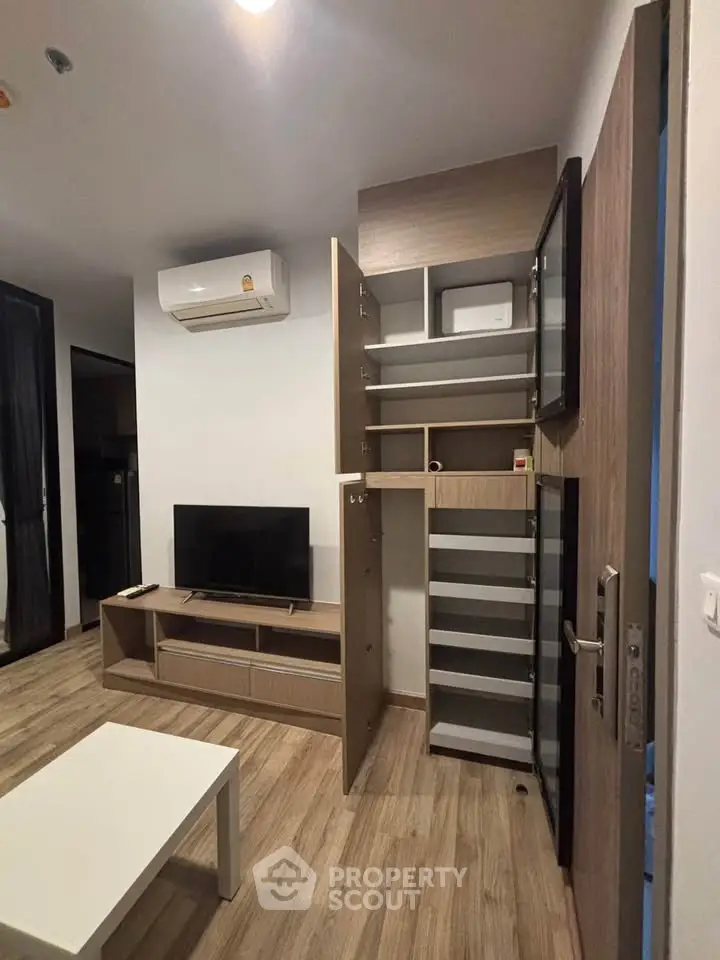 Modern living room with sleek storage, TV unit, and air conditioning in a stylish apartment.