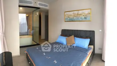 Luxurious bedroom with modern decor and ensuite bathroom featuring a glass partition and elegant artwork.