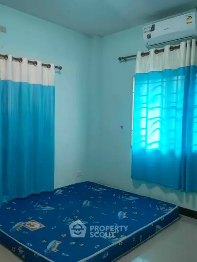 Cozy bedroom with blue curtains and mattress, featuring air conditioning for comfort.