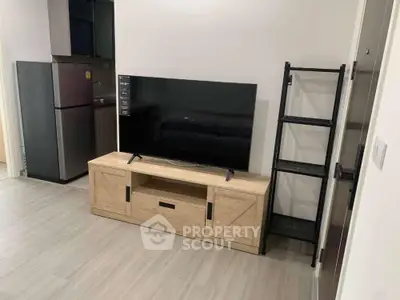 Modern living room with sleek TV setup and compact kitchen area.