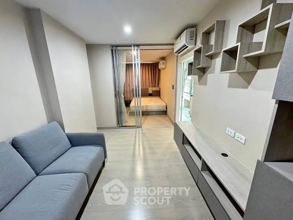 Modern living room with sleek furniture and sliding glass doors leading to a cozy bedroom.