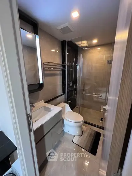 Modern bathroom with glass shower and sleek fixtures in luxury apartment.