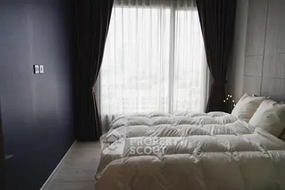 Cozy bedroom with large window and elegant curtains, offering a serene and inviting atmosphere.