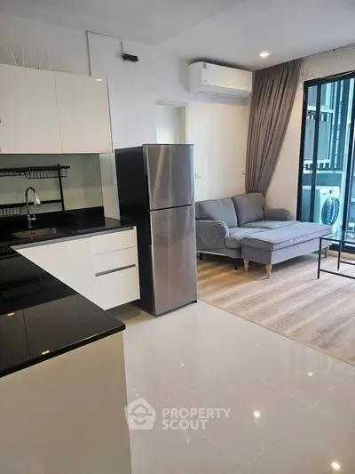 Modern open-layout kitchen and living room with sleek appliances and cozy seating area.