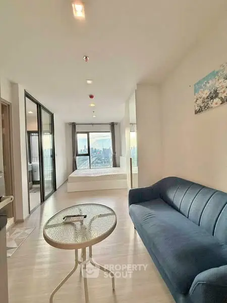 Modern open-plan living room with city view, featuring stylish furniture and natural light.
