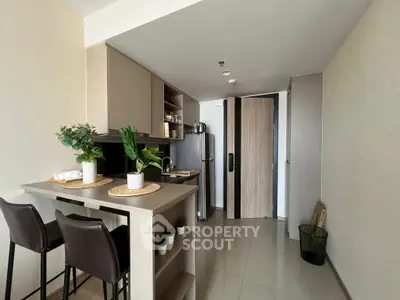Modern kitchen with sleek design, featuring a breakfast bar and stainless steel appliances in a cozy apartment.