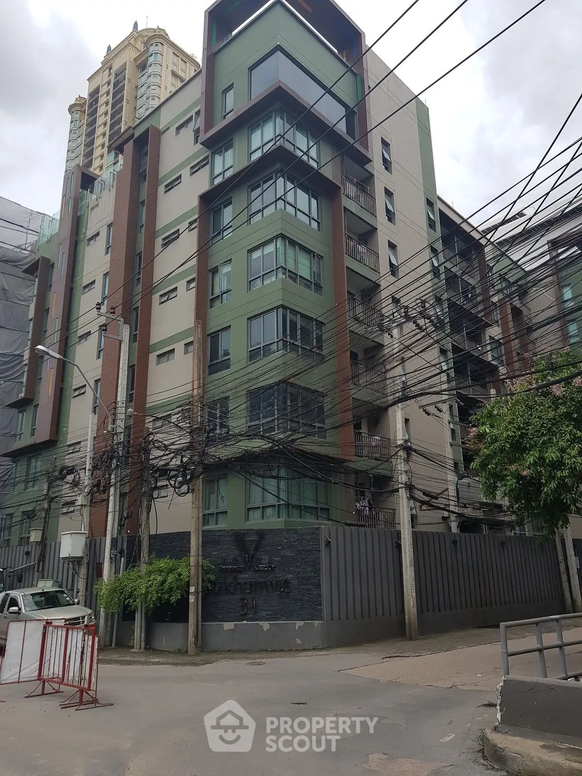 Modern urban apartment building with unique architectural design and multiple balconies in a bustling city area.