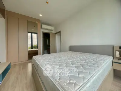 Spacious bedroom with large window and modern furnishings in a bright apartment.