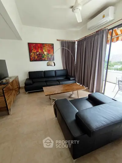 Modern living room with sleek black leather sofas and large window view