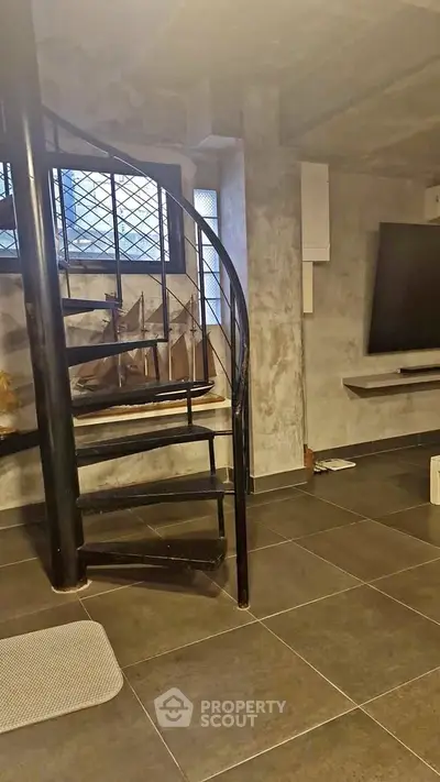 Modern industrial-style interior with spiral staircase and large TV