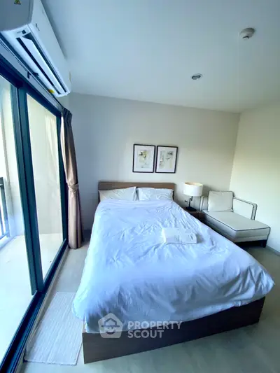 Modern bedroom with large window and cozy seating area, perfect for relaxation.