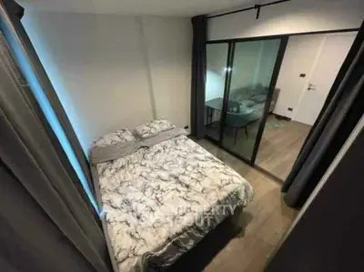 Cozy bedroom with modern decor and sliding glass doors leading to a stylish living area.