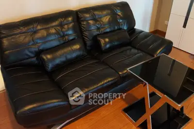 Modern black leather sofa in stylish living room with sleek glass coffee table.