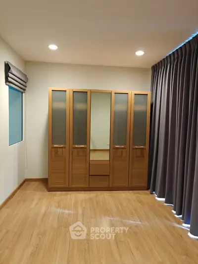 Spacious bedroom with wooden wardrobe and elegant curtains