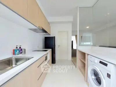 Modern kitchen with sleek cabinetry, washing machine, and open layout design.