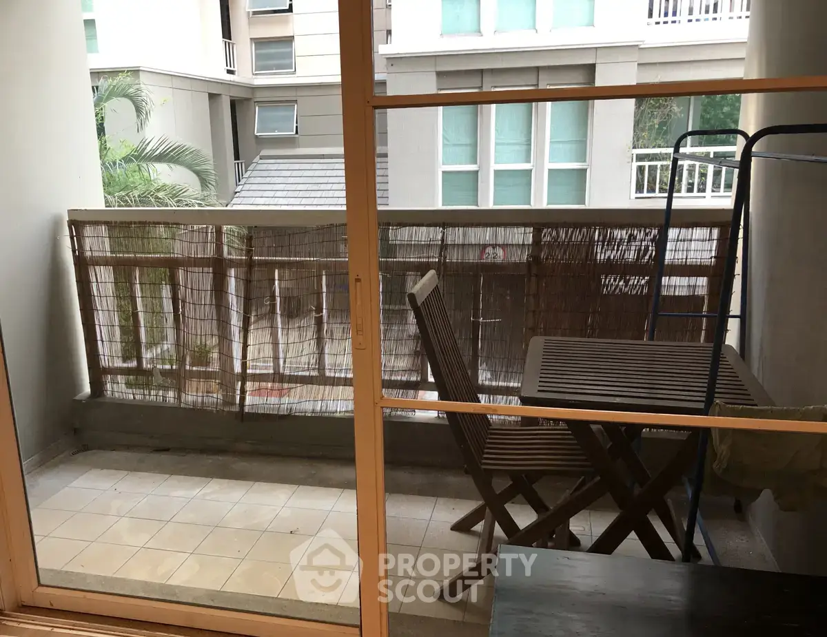 Charming balcony with cozy seating overlooking urban view, perfect for relaxation and enjoying fresh air.