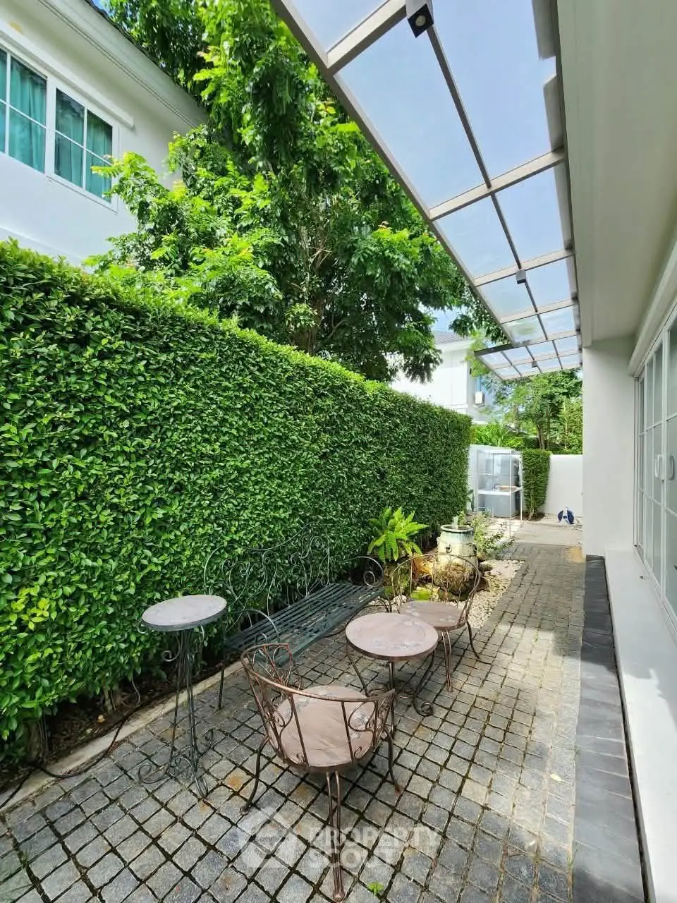 Charming outdoor patio with lush greenery and stylish seating, perfect for relaxation and entertaining.
