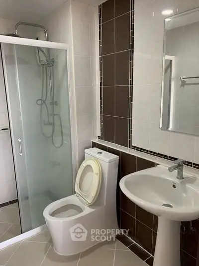 Modern bathroom with glass shower and sleek fixtures in contemporary apartment.