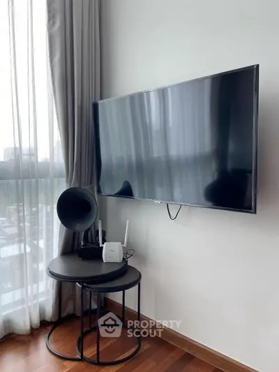 Modern living room corner with wall-mounted TV and stylish side table.