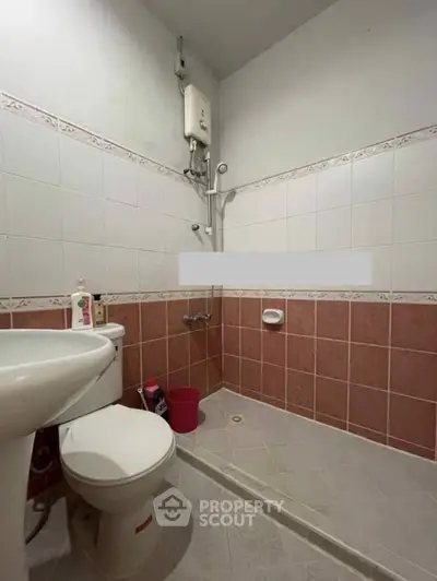 Compact bathroom with shower and toilet in tiled setting