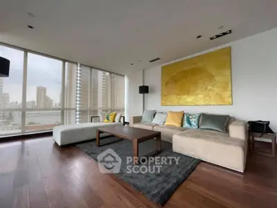 Spacious modern living room with large windows and city view, featuring elegant decor and wooden flooring.