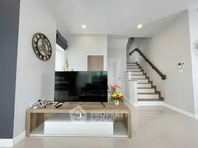 Modern living room with sleek TV setup and stylish staircase