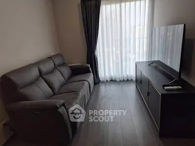 Modern living room with sleek sofa and large TV, featuring elegant curtains and wooden flooring.