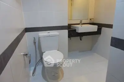 Modern bathroom with sleek white tiles and contemporary fixtures.