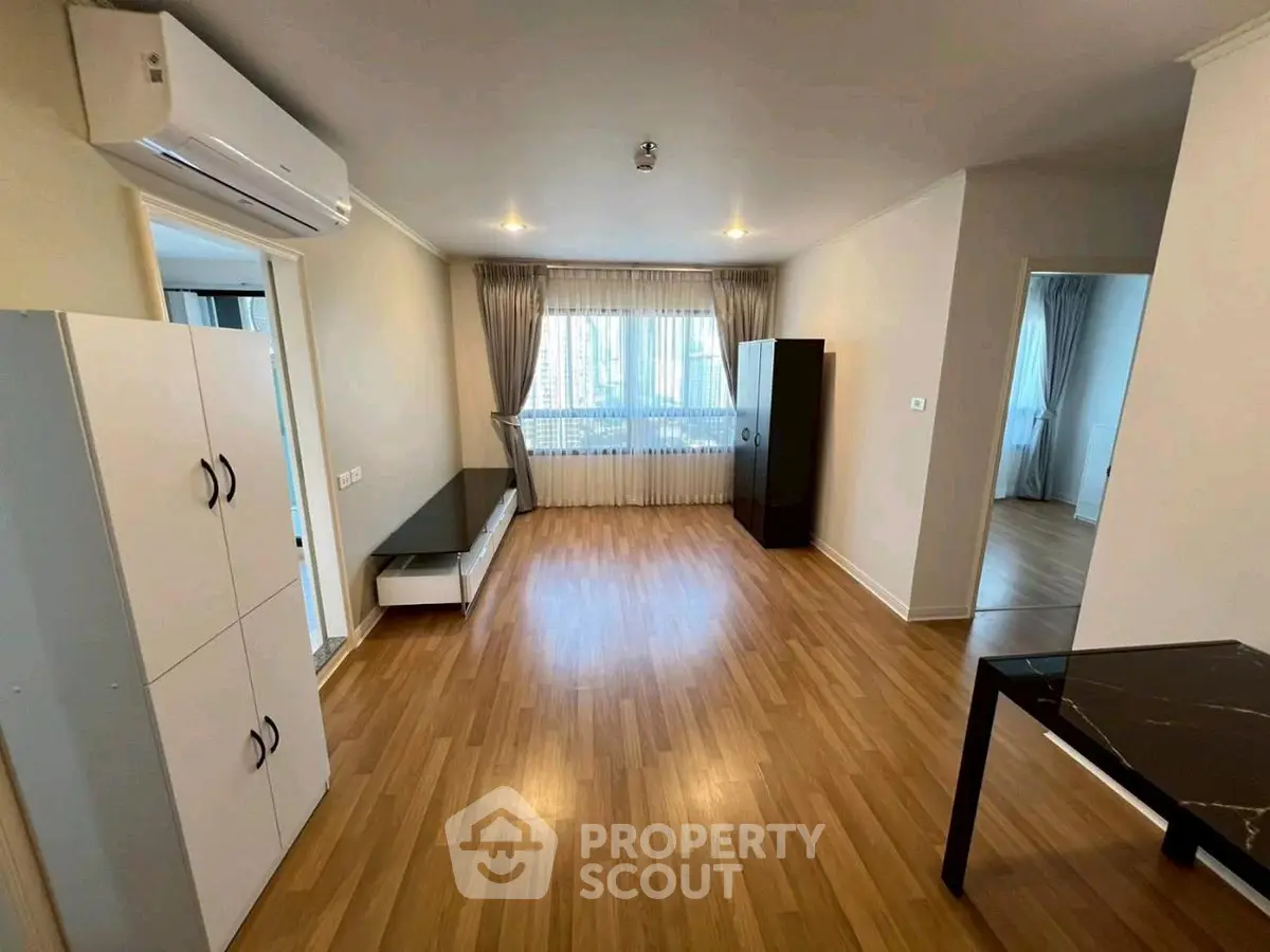 Spacious living room with wooden flooring and modern furnishings in a bright apartment.